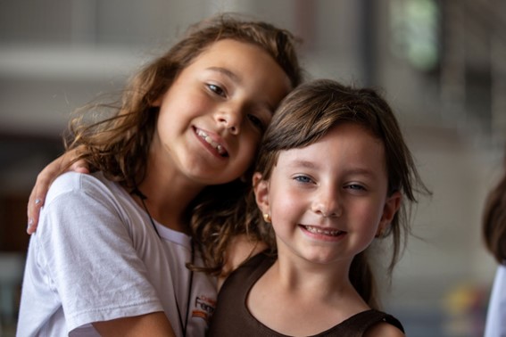 Duas meninas de aproximadamente sete anos abraçadas olhando para a câmera, para representar a geração Alpha
